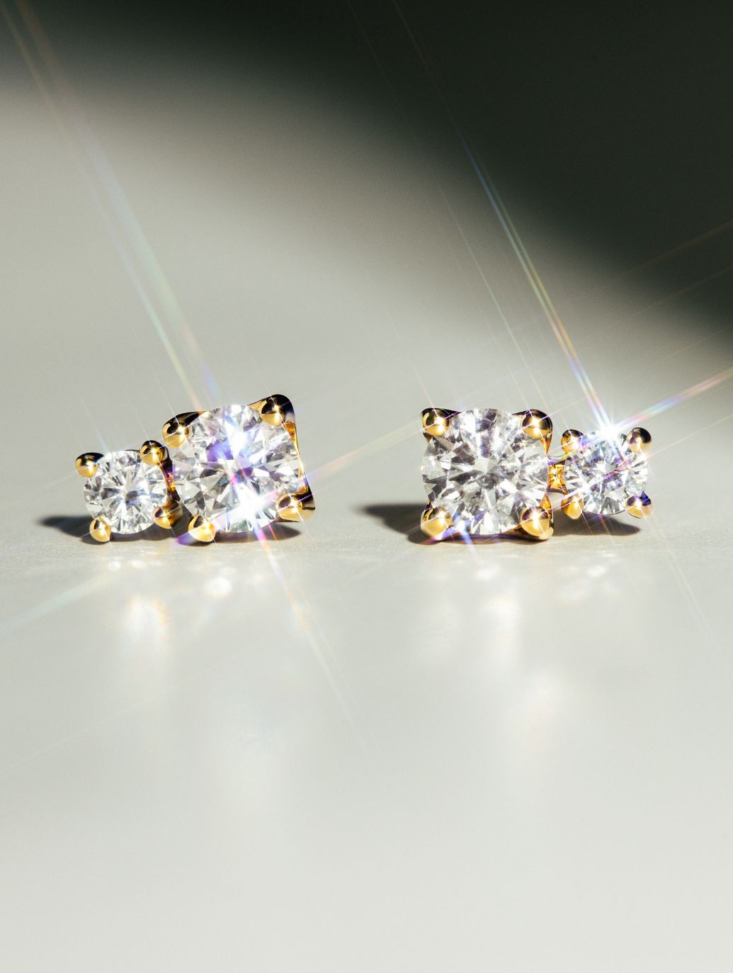 DUO LUMINA DS3014G Ohrstecker aus Gelbgold mit jeweils zwei funkelnden Diamanten in Krappenfassung, strahlend inszeniert auf hellem Untergrund.