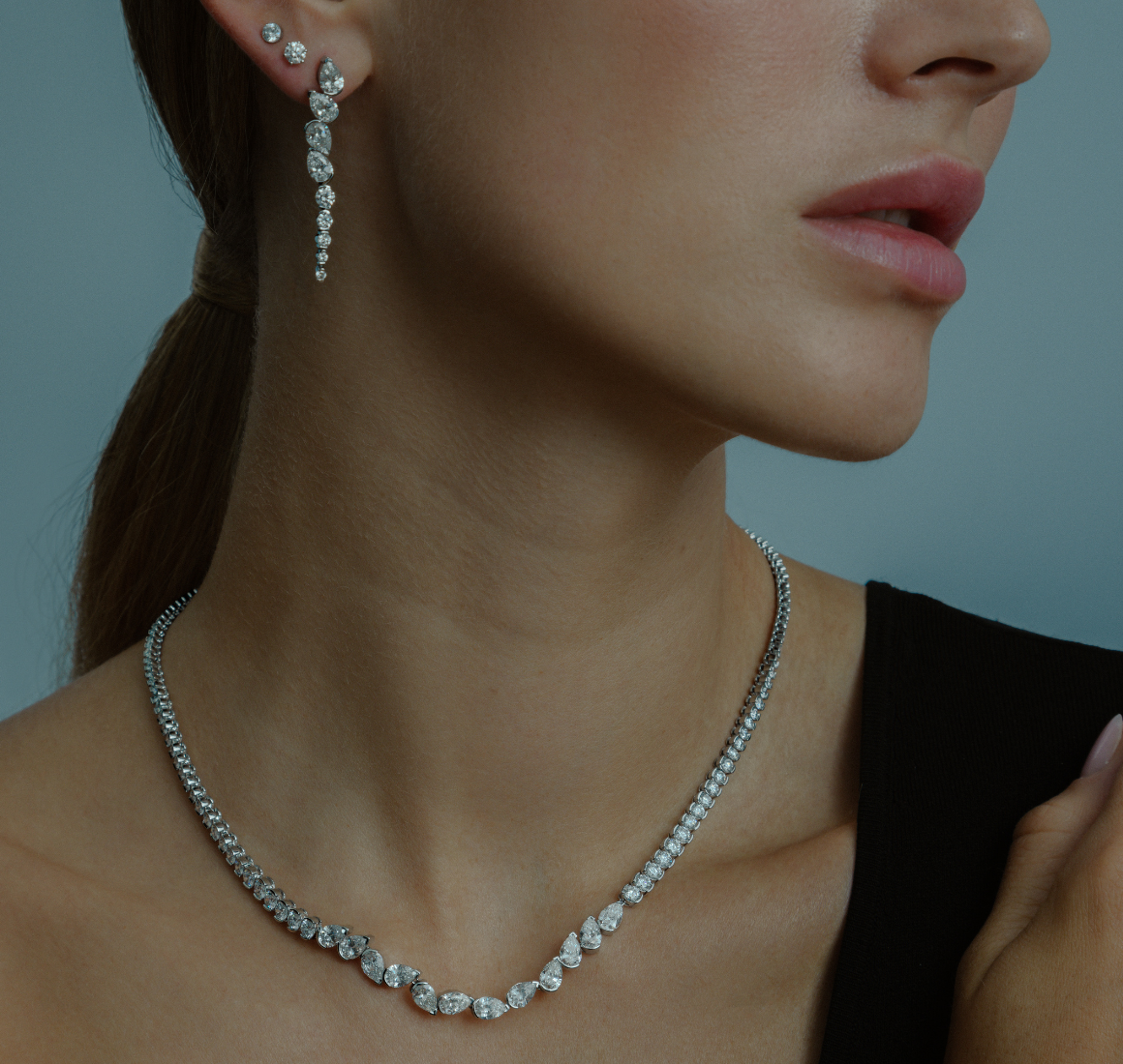 Nahaufnahme eines Models, dass die EDEN CHANDELIER Ohrringe und das EDEN RIVIERA Collier trägt.