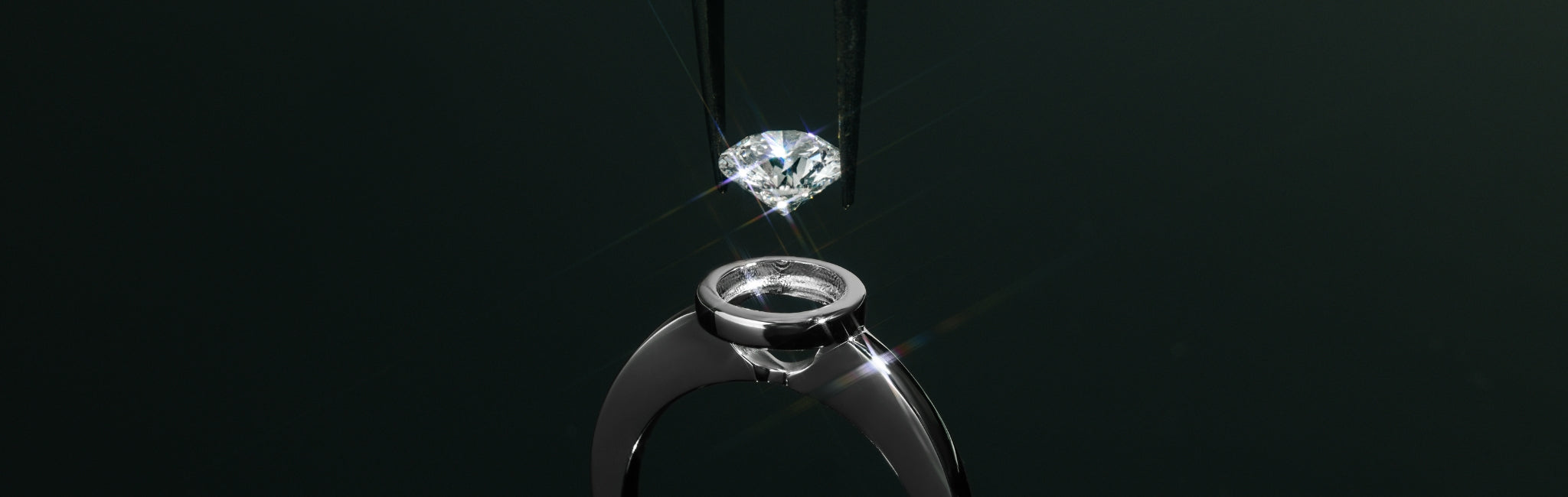 Nahaufnahme eines Solitärrings aus Weißgold mit offener Zargenfassung – ein Diamant wird mit einer Pinzette präzise über der Fassung gehalten, bereit zur Einfassung.