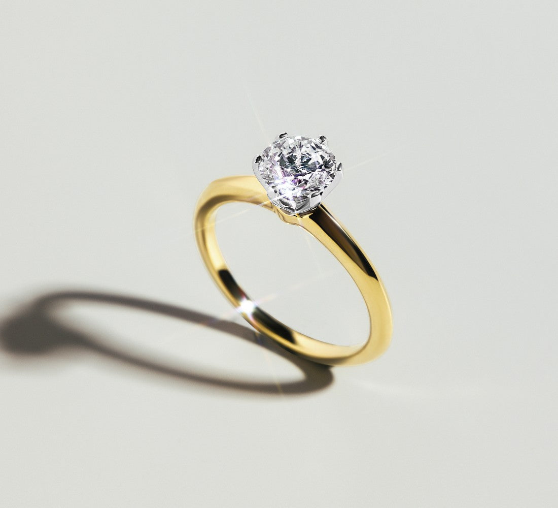 Eleganter BICOLOR Ring DS2062G aus Gelb- &amp; Weißgold mit funkelndem Solitär-Diamant in Krappenfassung auf hellem Untergrund.